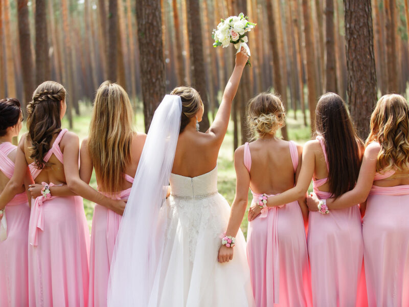 Bride and bridesmaids in pink dresses having fun at wedding day. Happy marriage and wedding party concept