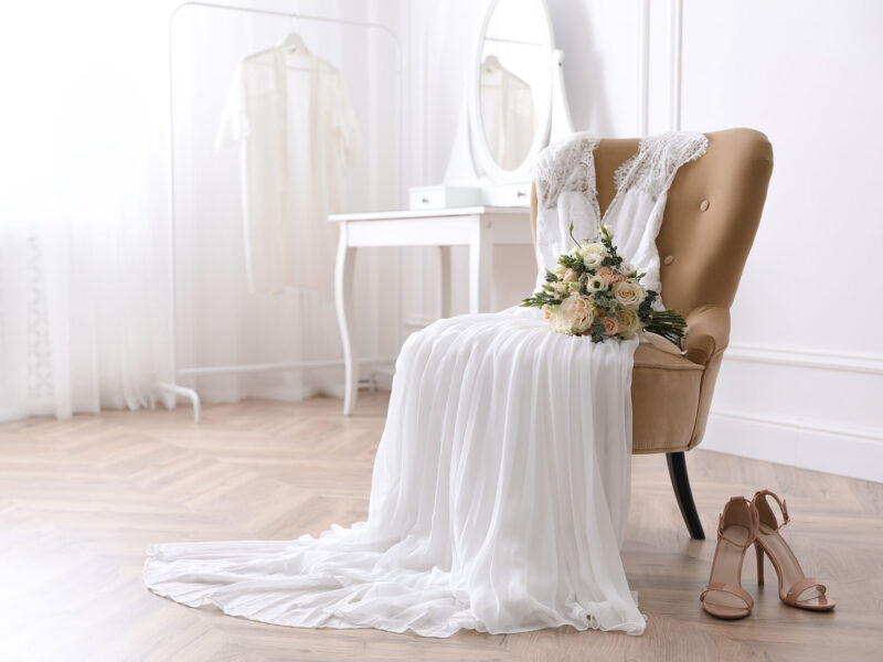 Elegant wedding dress, shoes and bouquet in room