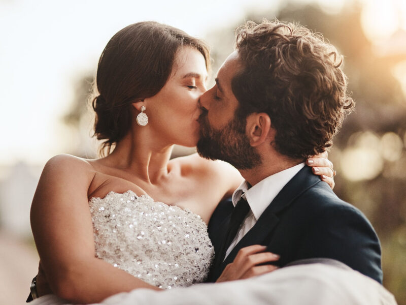 Love, wedding and kiss with a couple outdoor on their marriage day together for romance or tradition. Event, celebration or married with a birde and groom kissing outside after their ceremony
