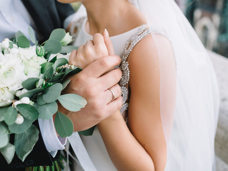 Close-up of groom's hand holding bride's wirst tender